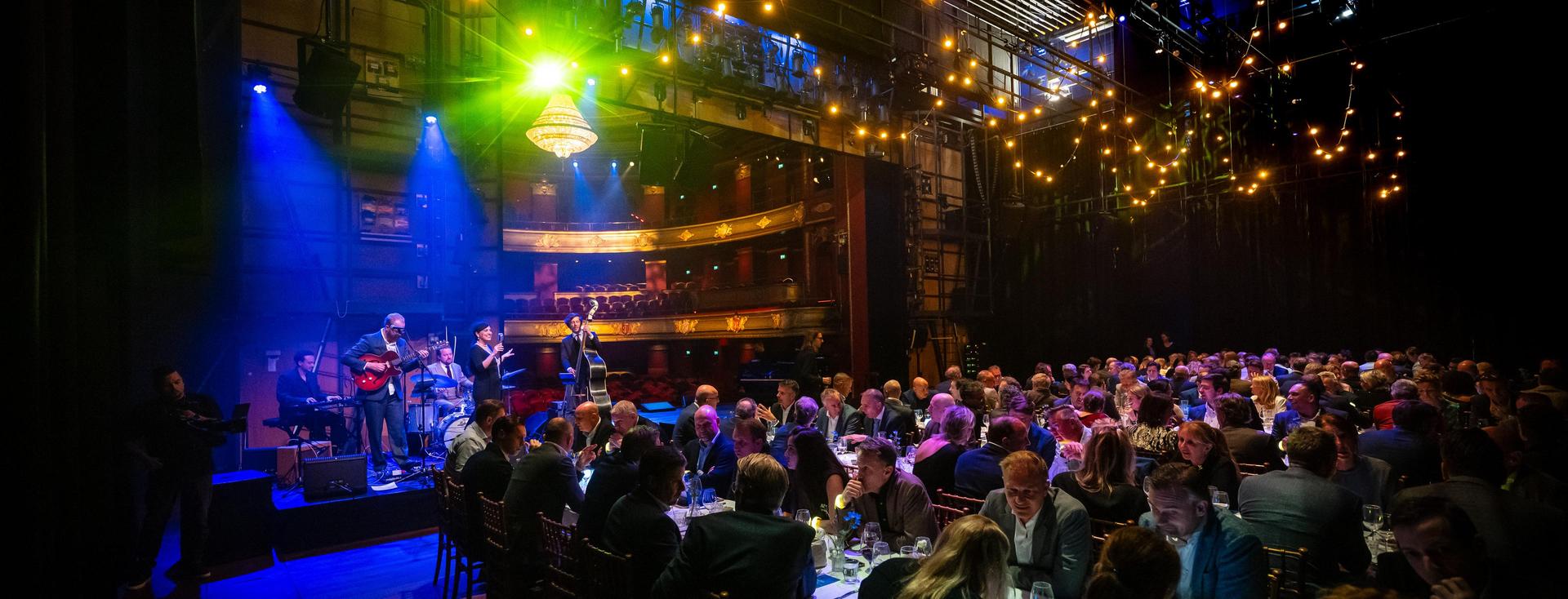 Dinerende gasten op het podium van Stadsschouwburg Haarlem bij SAP awardshow met live entertainment