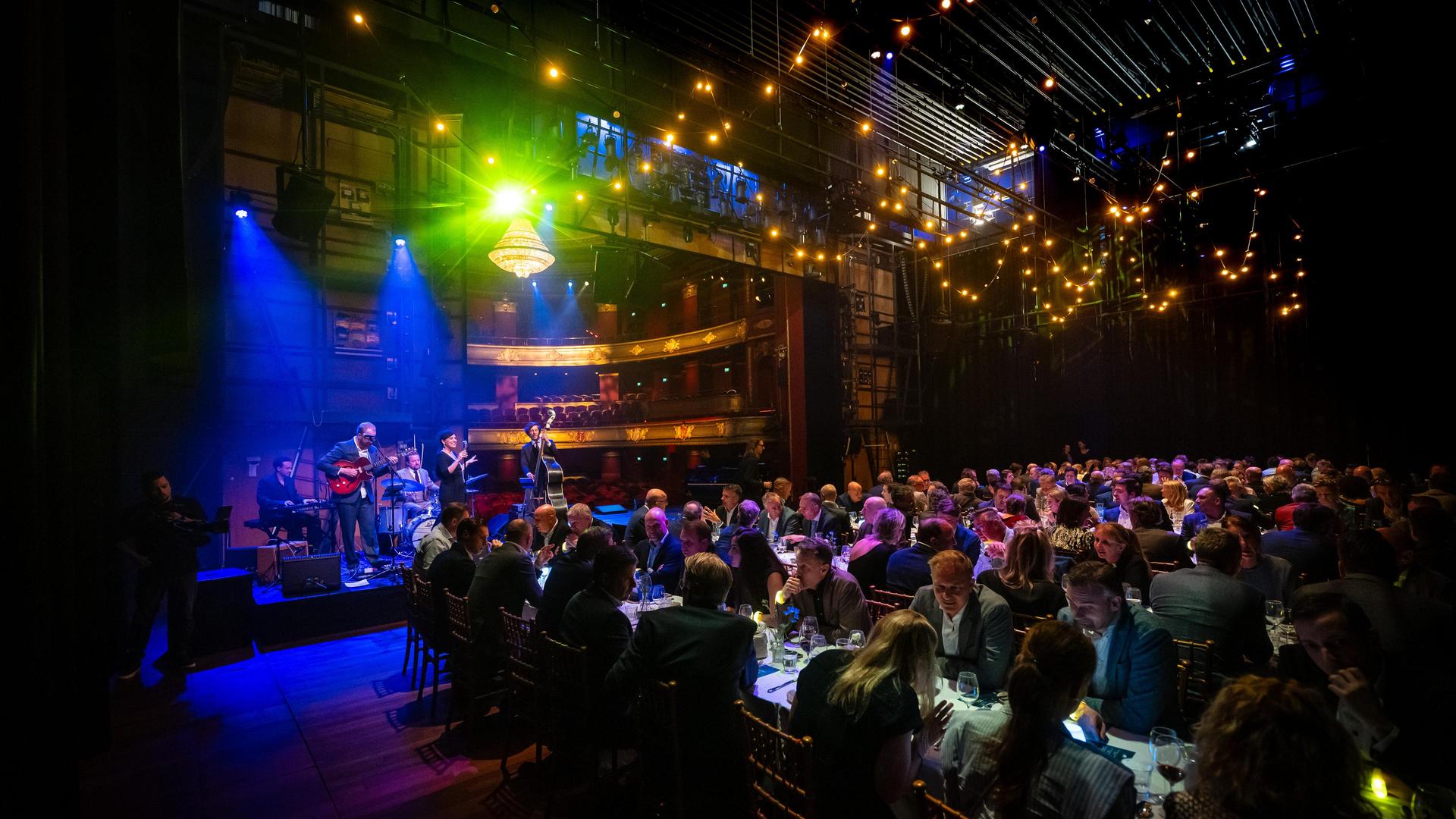 Dinerende gasten op podium van Stadsschouwburg Haarlem bij SAP awardshow met live muziek