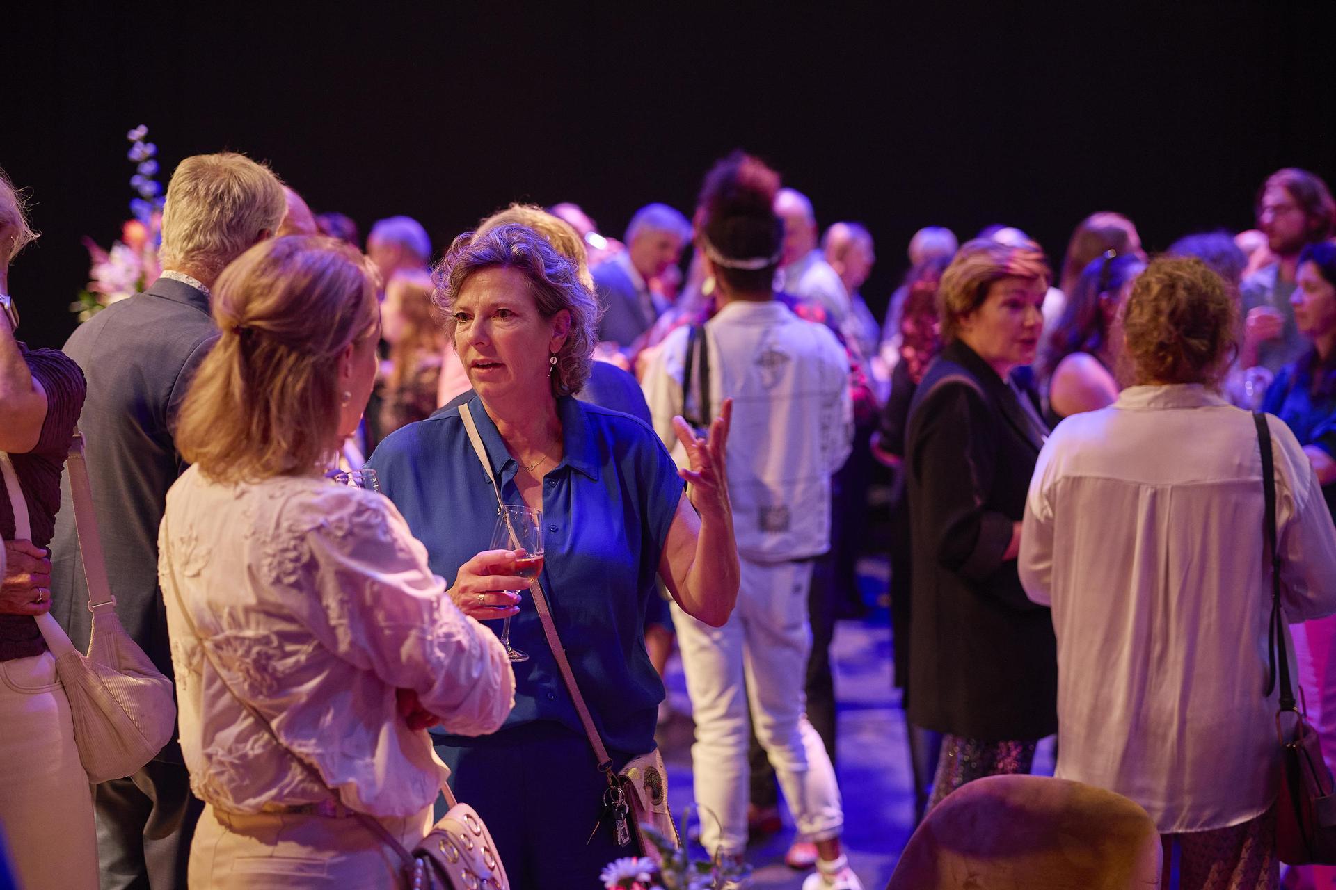 Gasten bij de borrel op het podium van de Schouwburg