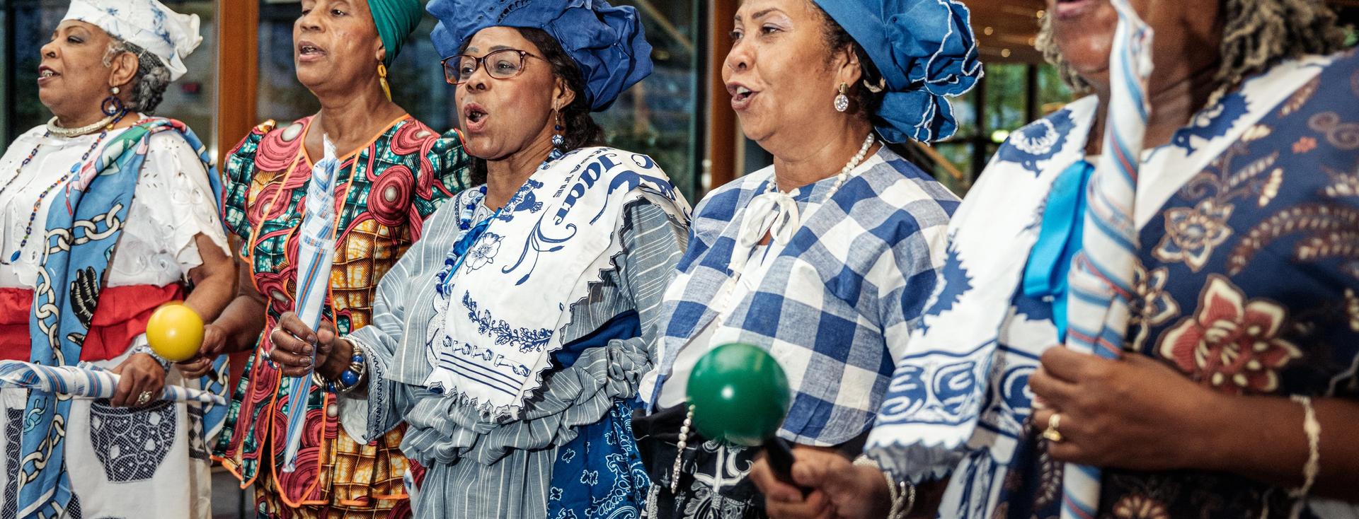 Vijf Surinaamse vrouwen zingen samen in een groep