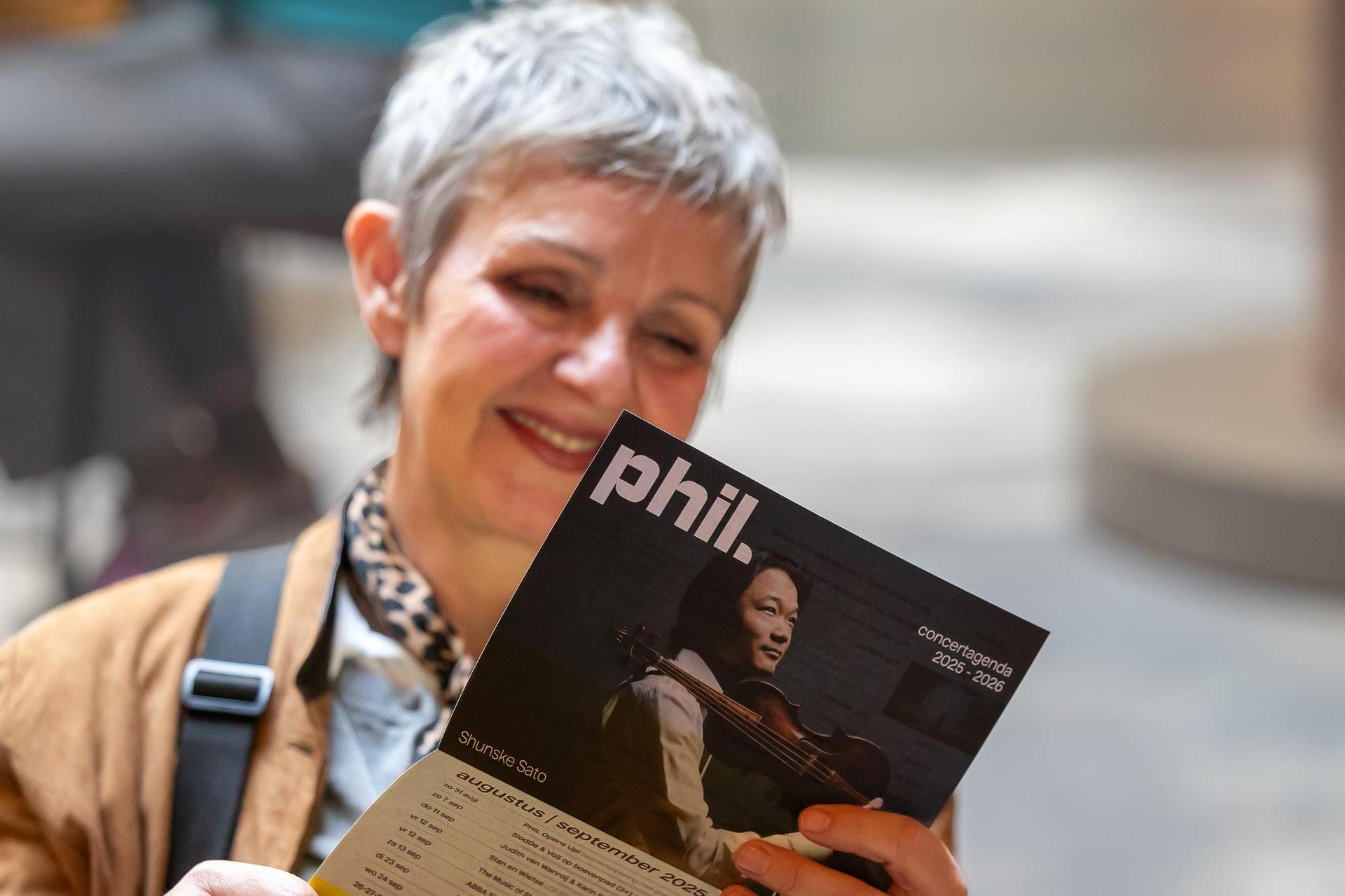 vrouw bekijkt PHIL brochure van het nieuwe seizoen