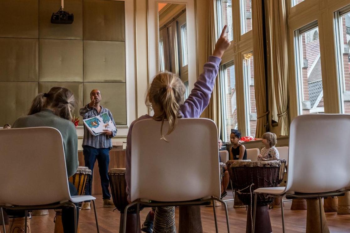 kind steekt haar hand op tijdens een muziekworkshop
