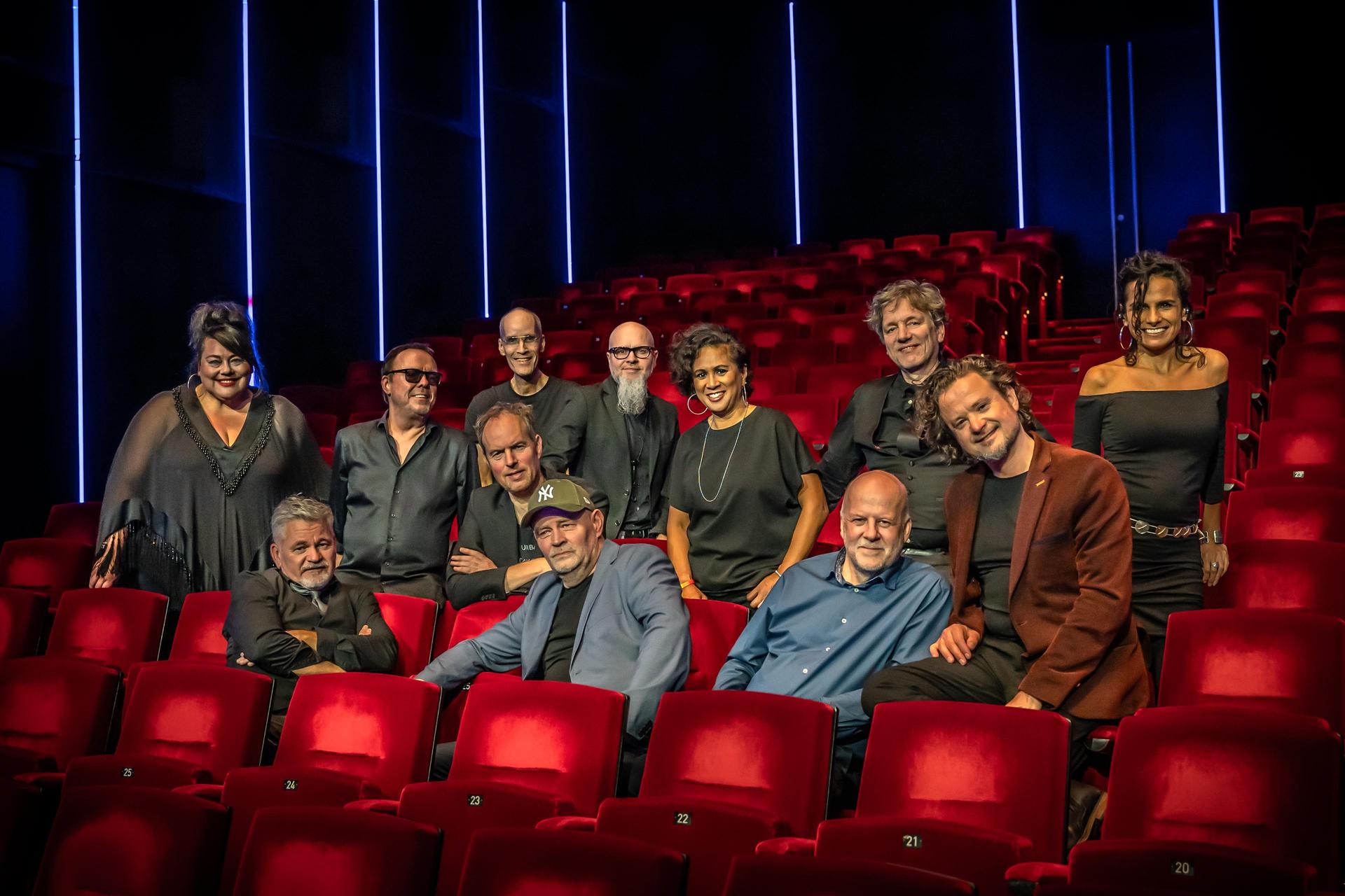 De band The Royal Dutch Scam zittend in een theaterzaal op rode stoelen