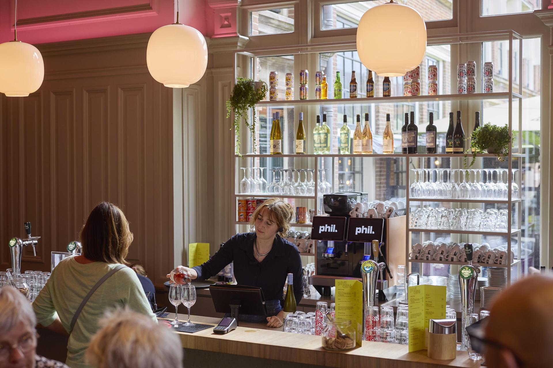 Horecamedewerker achter de bar van het PHIL Cafe