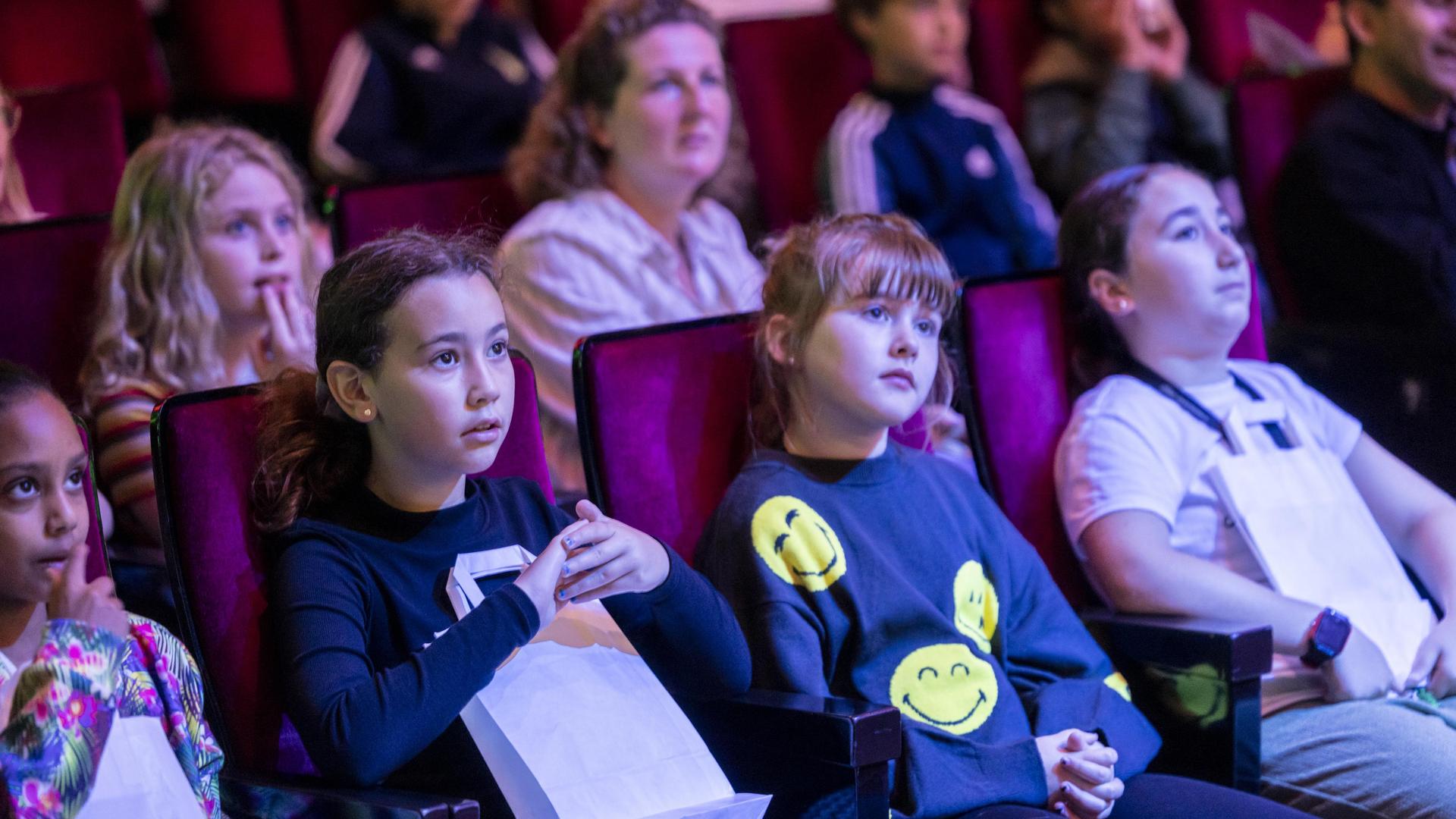 Kinderen zitten in hun stoel en kijken naar het concert