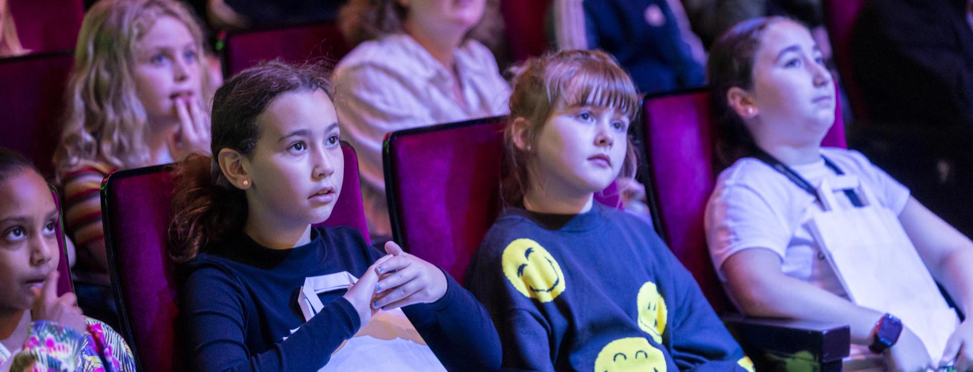 Kinderen zitten in hun stoel en kijken naar het concert