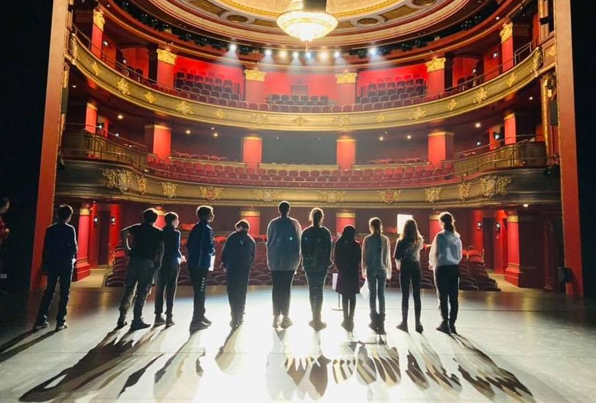 Kinderen staan op het podium van de Stadsschouwburg en kijken de zaal in